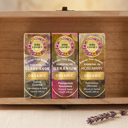 Organic essential oil trio set in a wooden box featuring Clary Sage, Geranium, and Rosemary bottles with lavender sprigs.
